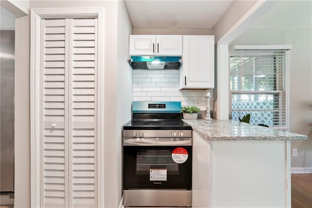 kitchen featuring hardwood / wood-style floors, backsplash, white cabinets, light stone counters, and stainless steel range oven