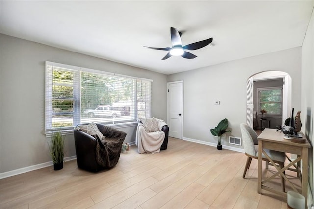 living area with ceiling fan, a wealth of natural light, and light hardwood / wood-style flooring