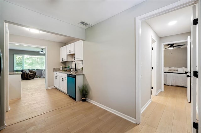 kitchen with white cabinetry, dishwasher, sink, tasteful backsplash, and light hardwood / wood-style floors