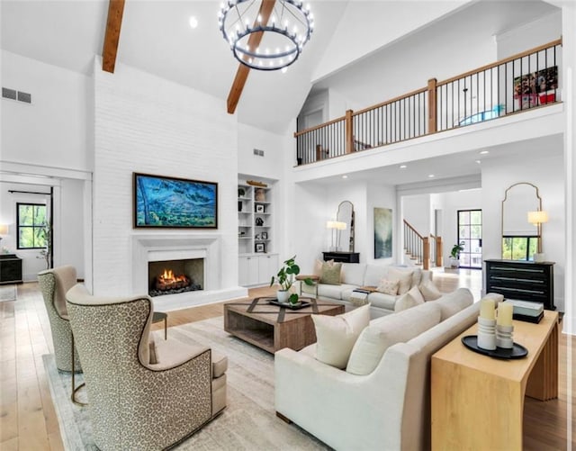 living room with a warm lit fireplace, high vaulted ceiling, a chandelier, and visible vents