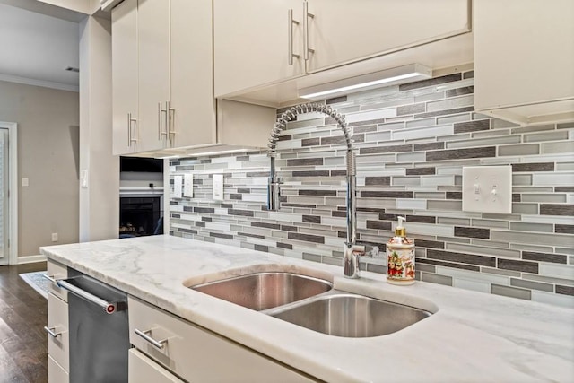 kitchen featuring a sink, backsplash, ornamental molding, dark wood-style flooring, and stainless steel dishwasher