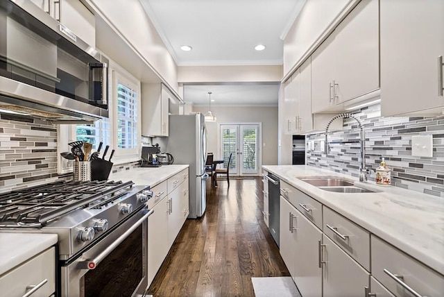 kitchen featuring stainless steel appliances, a sink, ornamental molding, backsplash, and dark wood finished floors