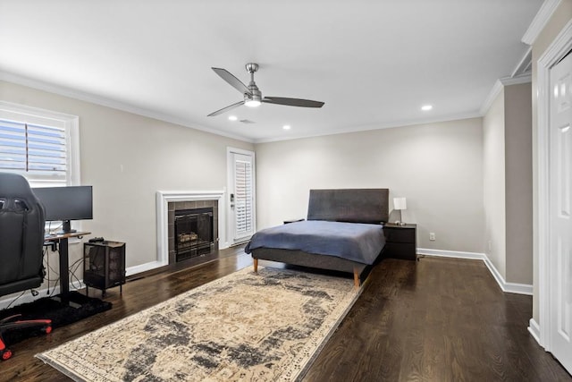 bedroom featuring dark wood finished floors, recessed lighting, baseboards, ornamental molding, and a tiled fireplace