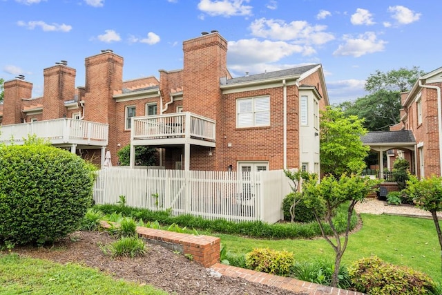back of house featuring brick siding, fence, and a chimney