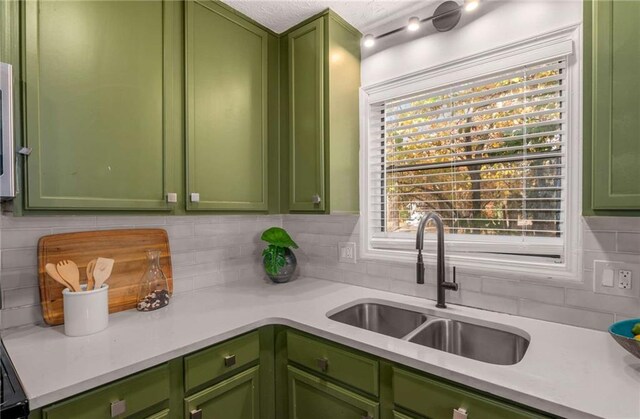 kitchen with green cabinets, decorative backsplash, and sink