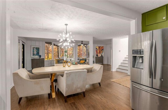 dining space featuring hardwood / wood-style floors, a notable chandelier, and a textured ceiling