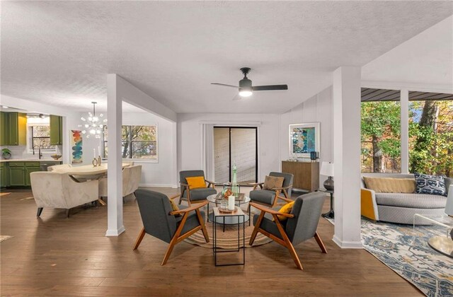 living area featuring wood-type flooring, ceiling fan with notable chandelier, a textured ceiling, and vaulted ceiling