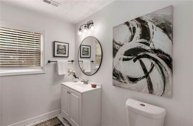 bathroom with vanity, toilet, and a textured ceiling