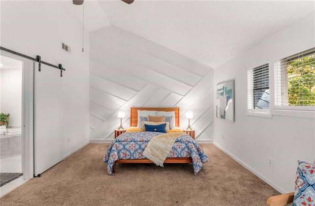 carpeted bedroom featuring a barn door, ceiling fan, ensuite bath, and lofted ceiling