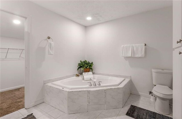 bathroom featuring tile patterned floors, toilet, and tiled bath