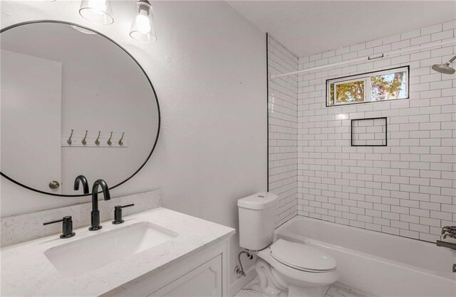 full bathroom featuring vanity, tiled shower / bath combo, and toilet