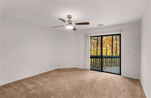 carpeted spare room featuring ceiling fan and a textured ceiling