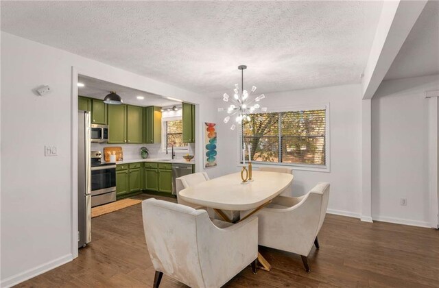 dining area with sink, dark wood-type flooring, a textured ceiling, and a notable chandelier