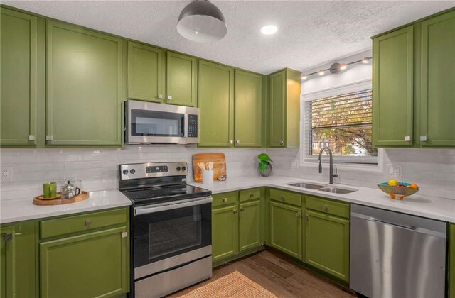 kitchen with backsplash, green cabinets, sink, a textured ceiling, and appliances with stainless steel finishes