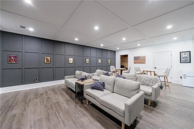 cinema room featuring recessed lighting, visible vents, light wood-type flooring, and a decorative wall