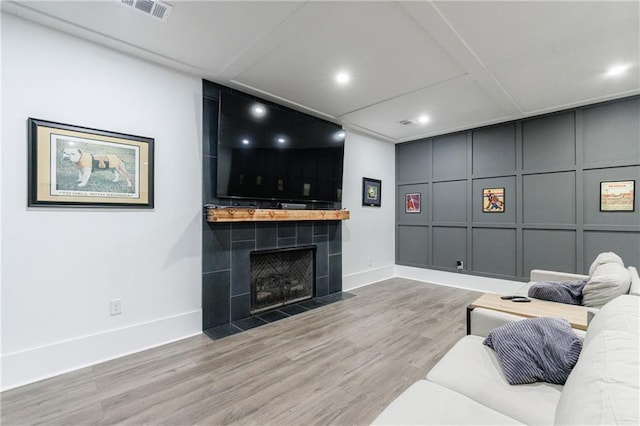 living room with visible vents, a decorative wall, wood finished floors, baseboards, and recessed lighting