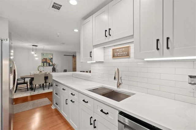 kitchen featuring decorative backsplash, a sink, light countertops, white cabinets, and stainless steel appliances