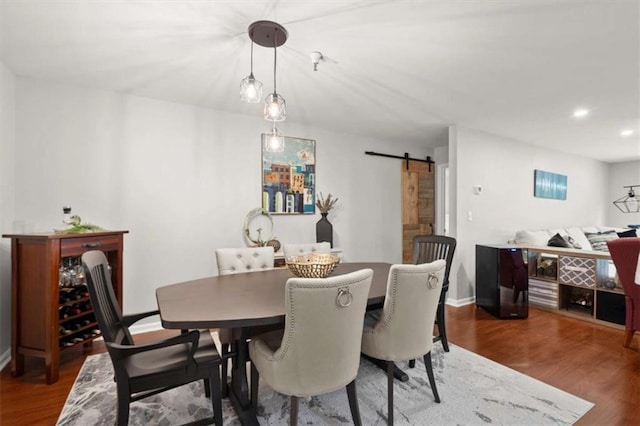dining area with baseboards, a barn door, wood finished floors, and recessed lighting