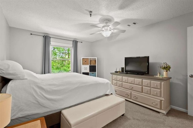 carpeted bedroom featuring a ceiling fan and a textured ceiling