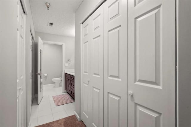 bathroom featuring a textured ceiling, tile patterned flooring, vanity, a closet, and toilet