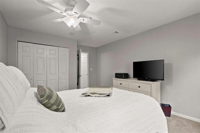bedroom with visible vents, a closet, baseboards, light colored carpet, and a textured ceiling