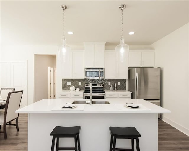 kitchen with stainless steel appliances, light countertops, and a kitchen island with sink