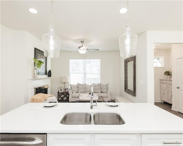 kitchen featuring light countertops, decorative light fixtures, a sink, and stainless steel dishwasher