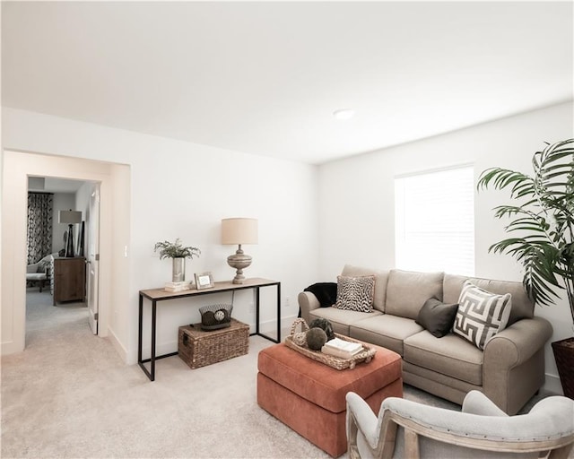 living area with baseboards and light colored carpet