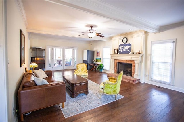 living room with dark wood-type flooring, crown molding, french doors, and a fireplace