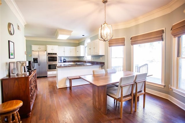 dining area featuring sink, dark hardwood / wood-style floors, ornamental molding, and an inviting chandelier