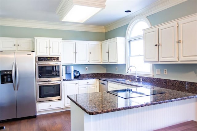 kitchen with kitchen peninsula, white cabinets, sink, and stainless steel appliances