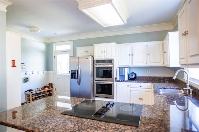 kitchen featuring sink, stainless steel appliances, white cabinetry, and dark stone counters