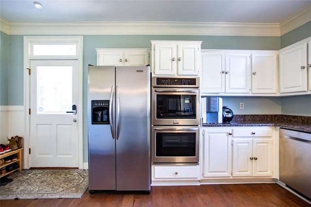 kitchen featuring white cabinets, stainless steel appliances, crown molding, and dark wood-type flooring