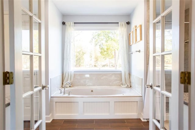 bathroom featuring a wealth of natural light, a bath, and french doors