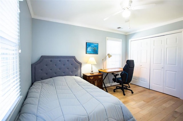 bedroom with a closet, ceiling fan, crown molding, and light wood-type flooring