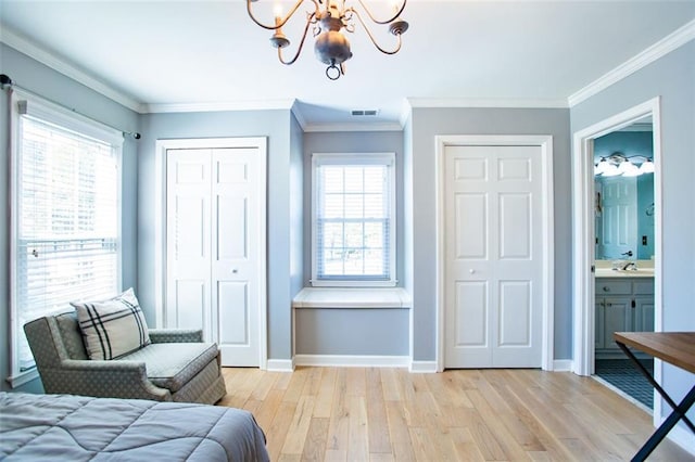 bedroom with multiple closets, light hardwood / wood-style flooring, ensuite bathroom, ornamental molding, and an inviting chandelier