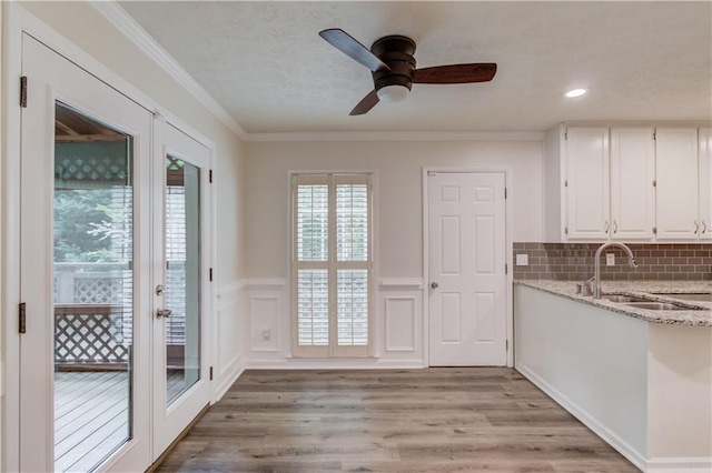 6006 Lanier Heights Cir, Buford, GA 30518 - unfurnished dining area featuring french doors, wainscoting, light wood-style flooring, ceiling fan, and a sink