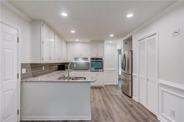 6006 Lanier Heights Cir, Buford, GA 30518 - kitchen with appliances with stainless steel finishes, a sink, ornamental molding, white cabinets, and under cabinet range hood