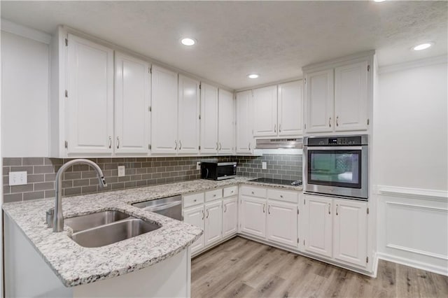 6006 Lanier Heights Cir, Buford, GA 30518 - kitchen with appliances with stainless steel finishes, a sink, white cabinets, a peninsula, and light stone counters