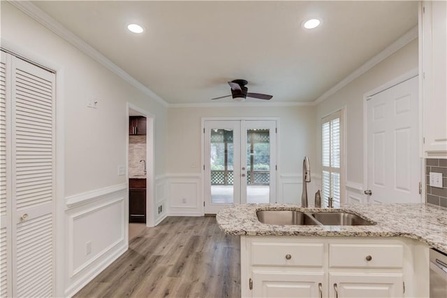 6006 Lanier Heights Cir, Buford, GA 30518 - kitchen with a sink, ceiling fan, light stone counters, light wood-type flooring, and a decorative wall