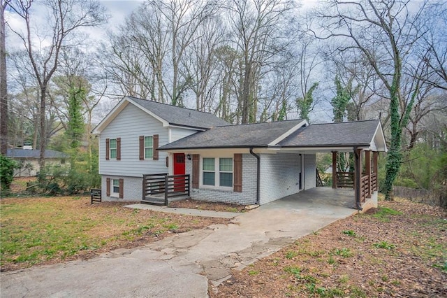 tri-level home featuring brick siding, an attached carport, and driveway