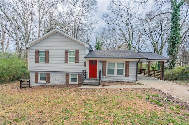 split level home featuring brick siding, driveway, a chimney, and a carport