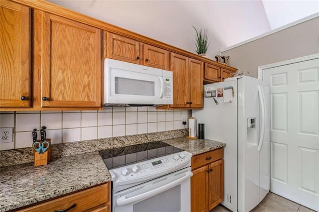 kitchen with decorative backsplash, white appliances, light stone counters, and light tile patterned floors