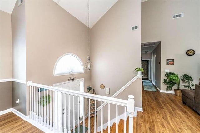 staircase with hardwood / wood-style flooring and high vaulted ceiling