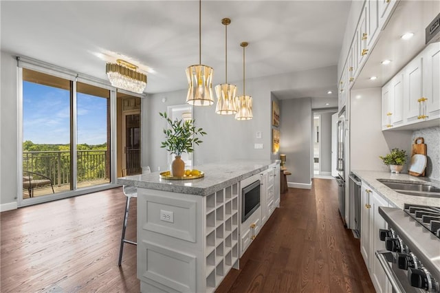 1820 Peachtree St NW Unit 804, Atlanta, GA 30309 - kitchen featuring a kitchen island, appliances with stainless steel finishes, white cabinets, a breakfast bar, and dark wood-style floors