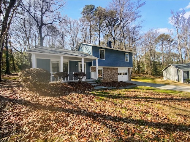 split level home featuring an attached garage, stone siding, driveway, and a porch