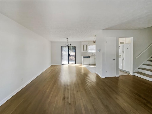 unfurnished living room with baseboards, stairway, and wood finished floors