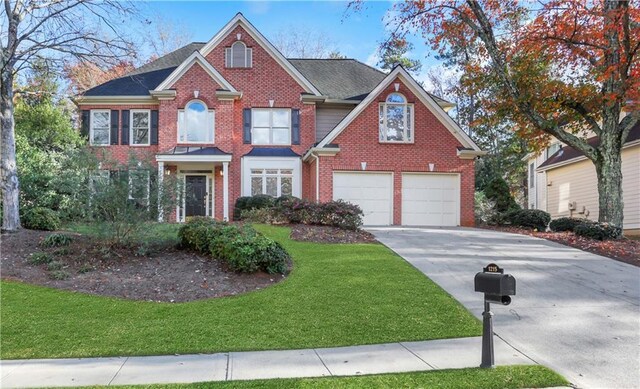 1215 Wynridge Xing, Alpharetta, GA 30005 - georgian-style home with driveway, an attached garage, brick siding, and a front lawn