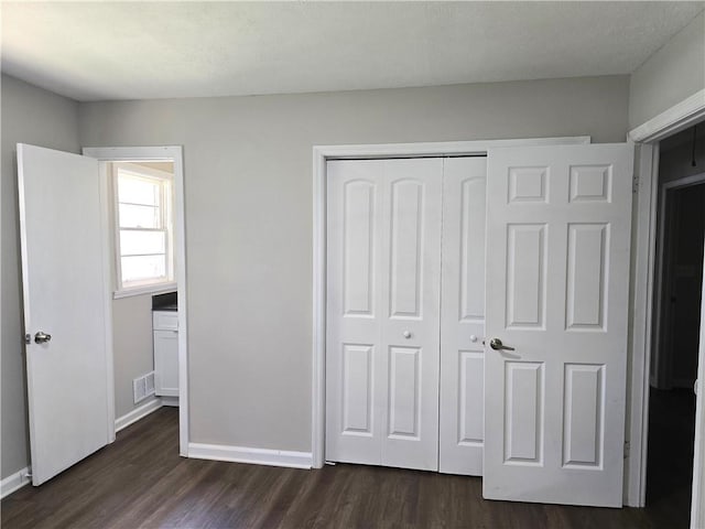 unfurnished bedroom featuring dark hardwood / wood-style flooring and a closet