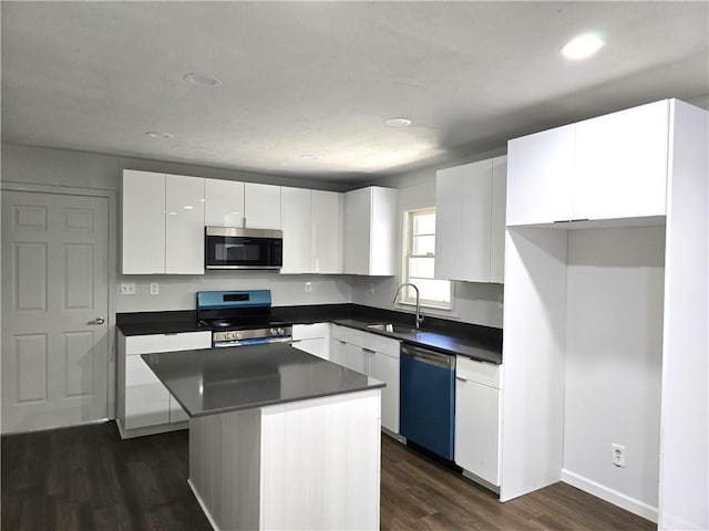 kitchen with sink, a center island, dark hardwood / wood-style floors, stainless steel appliances, and white cabinets